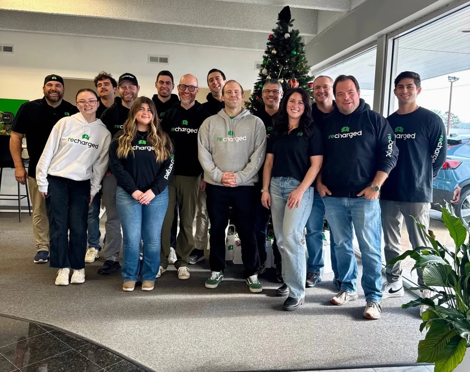 Recharged team members in a showroom by a holiday tree